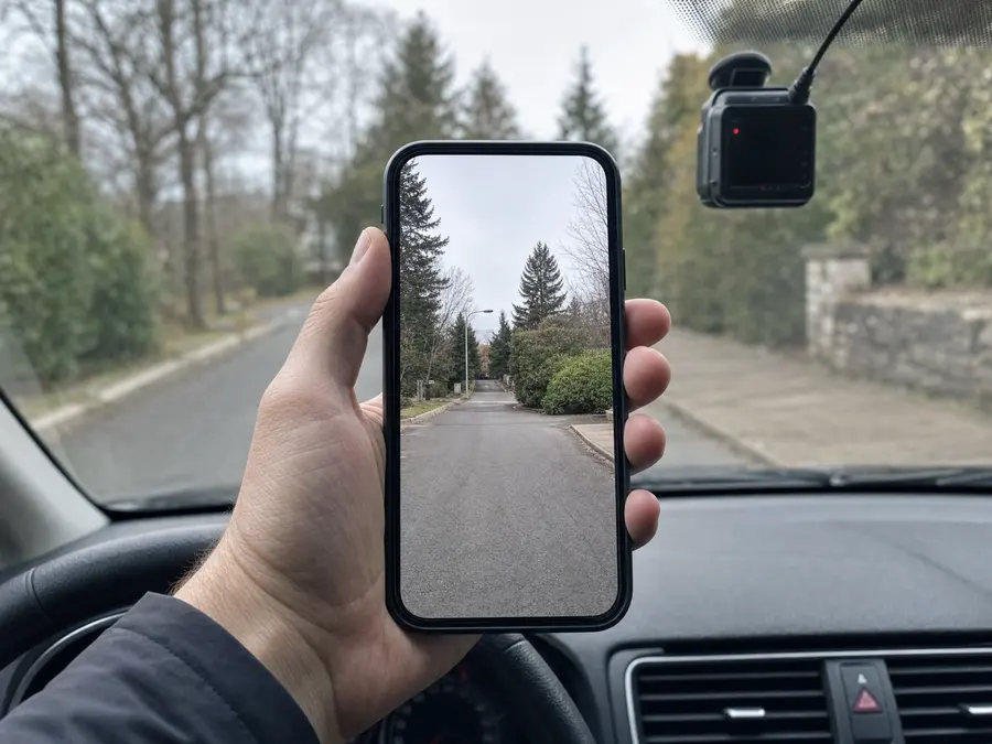 Araç içinde tutulan telefon, kameranın yol görüntüsünü canlı gösteriyor; kamera arkada, camda